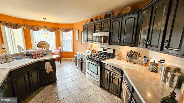 kitchen featuring sink, hanging light fixtures, stainless steel appliances, tasteful backsplash, and a notable chandelier