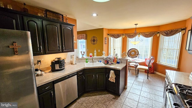 kitchen with kitchen peninsula, appliances with stainless steel finishes, pendant lighting, and sink