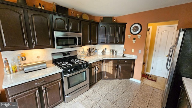 kitchen featuring tasteful backsplash, dark brown cabinetry, light tile patterned floors, and appliances with stainless steel finishes