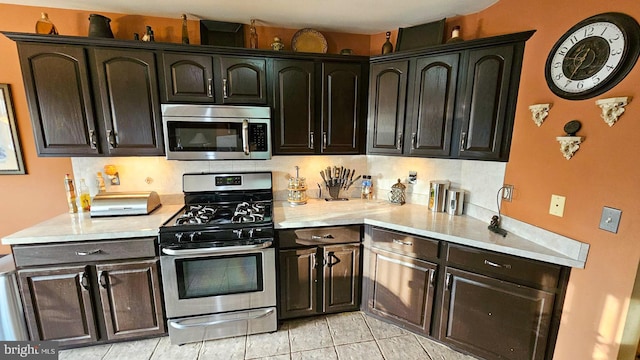 kitchen featuring decorative backsplash, dark brown cabinetry, light tile patterned floors, and appliances with stainless steel finishes