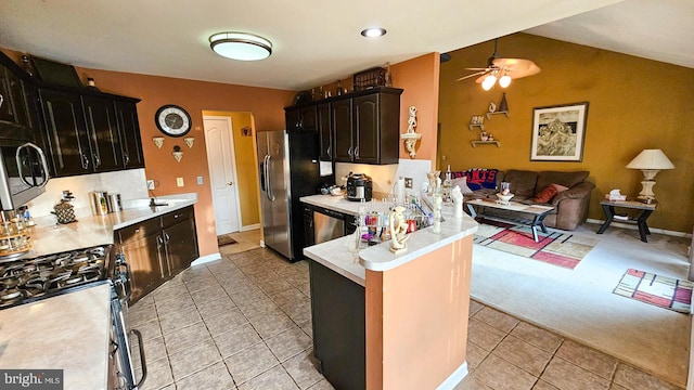 kitchen with lofted ceiling, ceiling fan, light tile patterned floors, kitchen peninsula, and stainless steel appliances