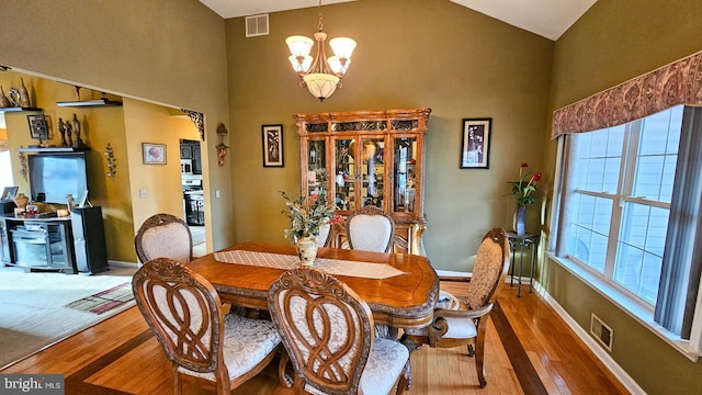 dining space with hardwood / wood-style floors, plenty of natural light, and an inviting chandelier