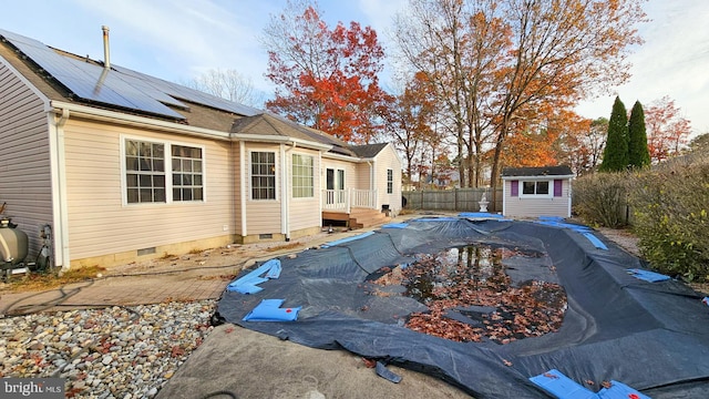 exterior space with a storage unit, solar panels, and a covered pool