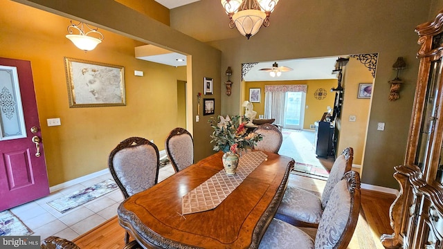 dining area with ceiling fan with notable chandelier and light hardwood / wood-style floors