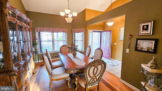 dining area featuring a notable chandelier, light hardwood / wood-style floors, and lofted ceiling