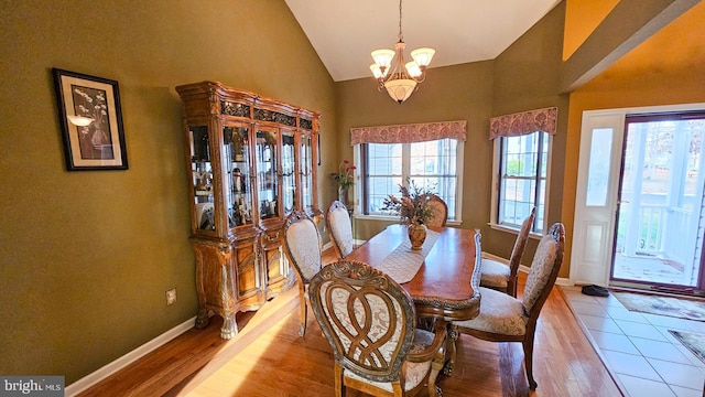 dining room with a chandelier, lofted ceiling, light wood-type flooring, and a healthy amount of sunlight