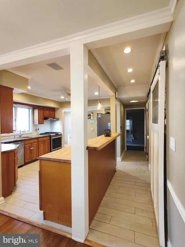 kitchen featuring wood counters, a barn door, appliances with stainless steel finishes, and light hardwood / wood-style flooring