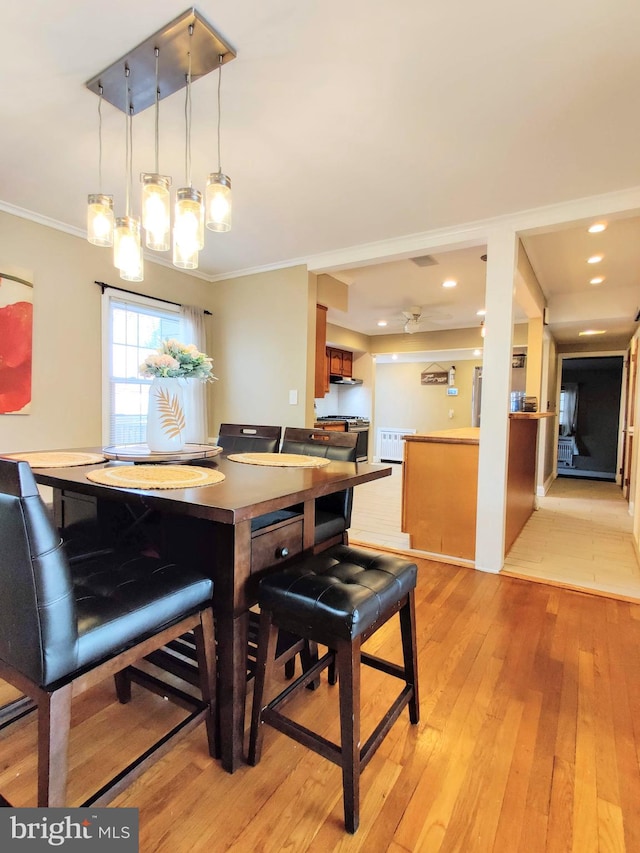 dining area with light hardwood / wood-style flooring and ornamental molding