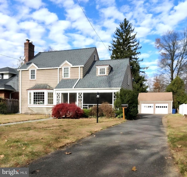 new england style home with a front yard, an outdoor structure, and a garage