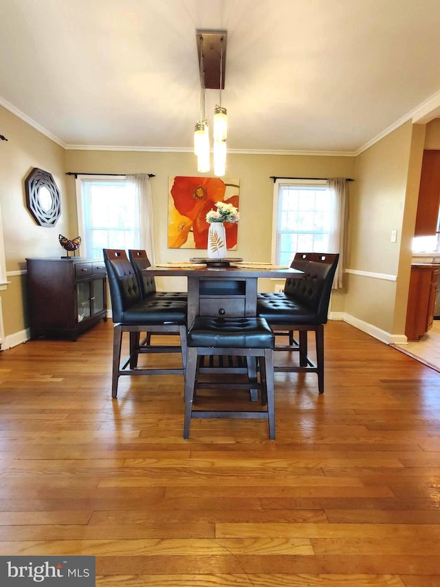 dining space featuring hardwood / wood-style flooring, a healthy amount of sunlight, and ornamental molding