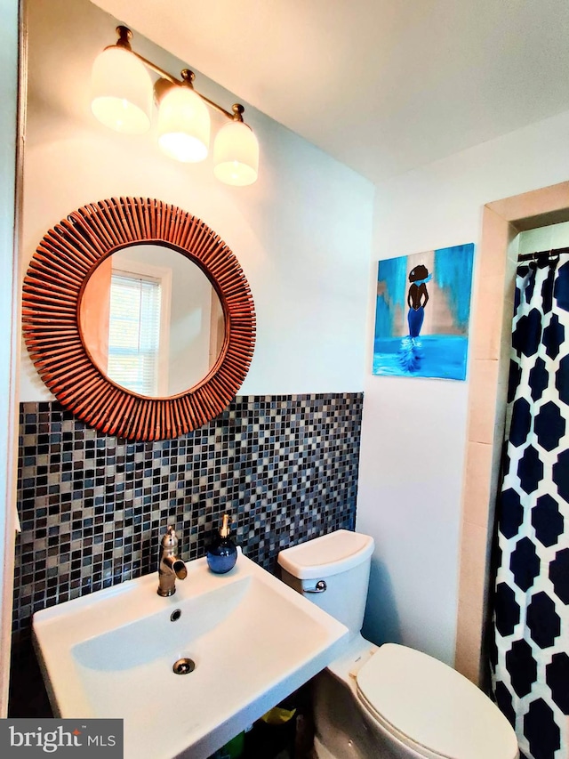 bathroom featuring toilet, tile walls, and sink