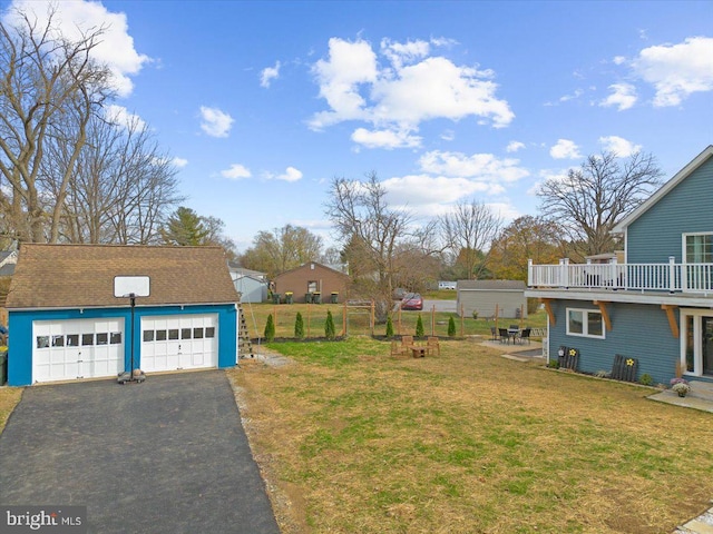 view of yard featuring a garage, an outdoor structure, and a balcony