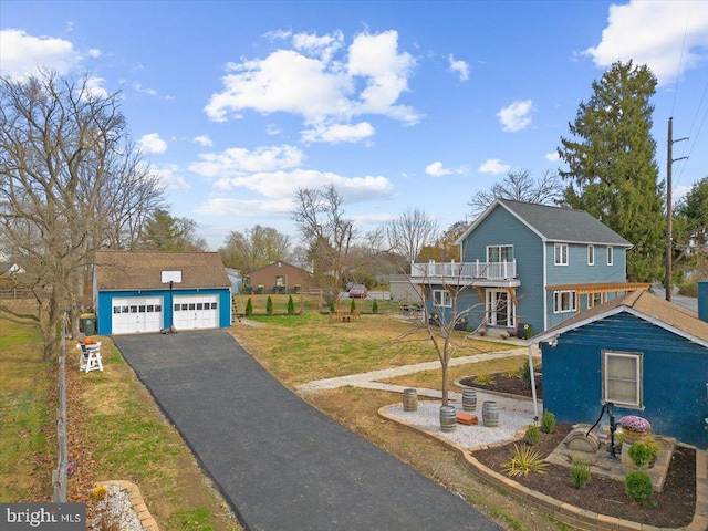 view of front of house with an outbuilding, a balcony, a garage, and a front yard