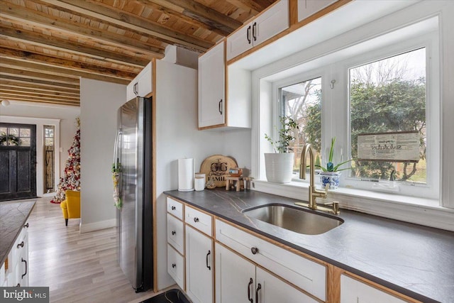 kitchen featuring sink, light hardwood / wood-style flooring, stainless steel fridge, white cabinets, and wood ceiling