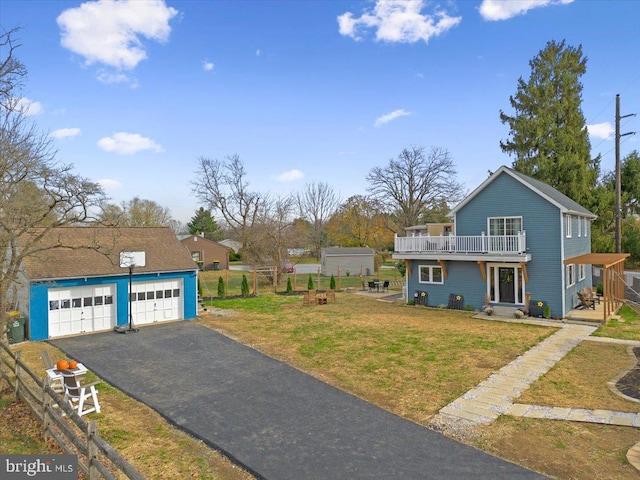 view of front of house with a balcony, an outbuilding, and a front yard