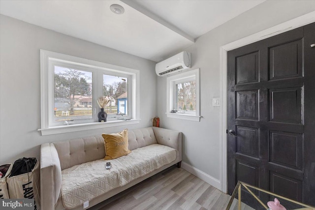 sitting room featuring light wood-type flooring and an AC wall unit