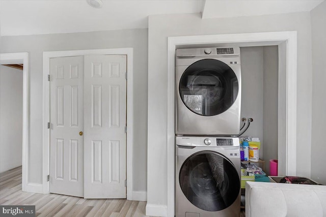 washroom with stacked washing maching and dryer and light hardwood / wood-style flooring