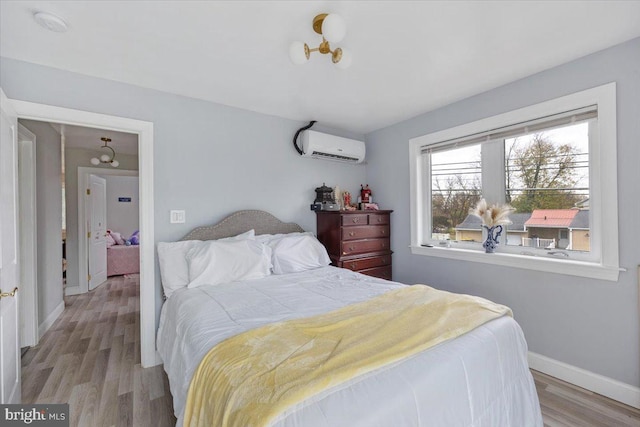 bedroom featuring a wall mounted AC and light hardwood / wood-style floors