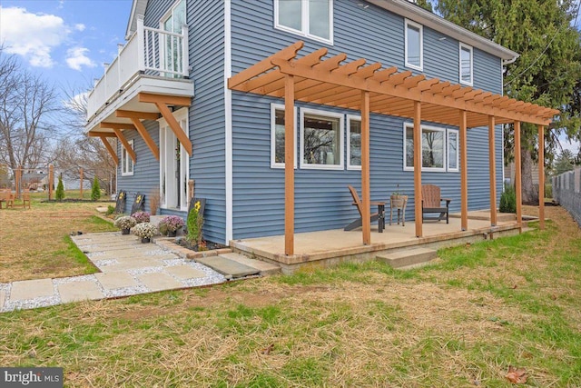 view of side of property featuring a pergola, a balcony, a patio area, and a lawn