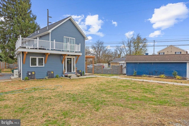 rear view of property featuring a yard and a balcony