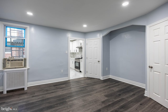 unfurnished living room with dark hardwood / wood-style floors, cooling unit, and radiator heating unit