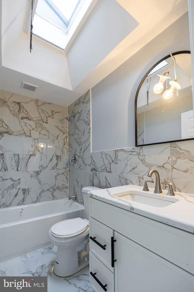 full bathroom with a skylight, tub / shower combination, toilet, vanity, and tile walls