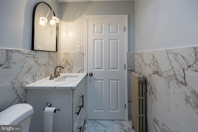 bathroom with radiator heating unit, vanity, toilet, and tile walls