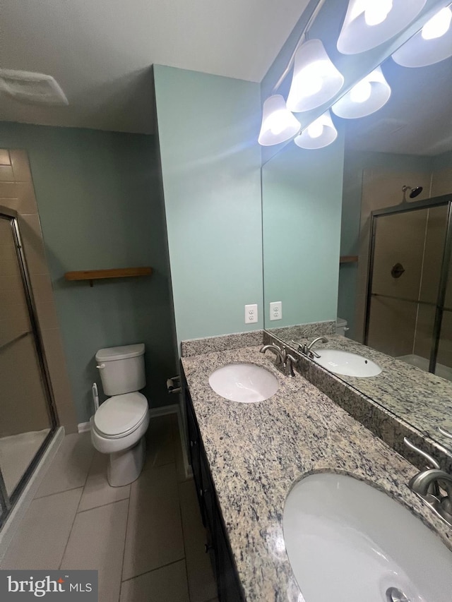 bathroom featuring tile patterned floors, vanity, toilet, and a shower with shower door