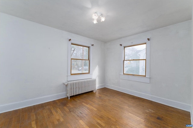 unfurnished room featuring a wealth of natural light, dark wood-type flooring, and radiator