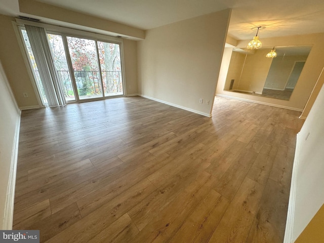 unfurnished room featuring hardwood / wood-style flooring and an inviting chandelier