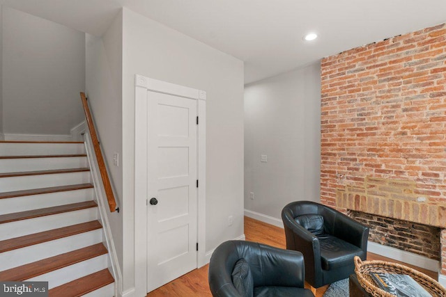 sitting room featuring brick wall and light wood-type flooring