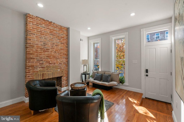 sitting room with hardwood / wood-style flooring and a brick fireplace