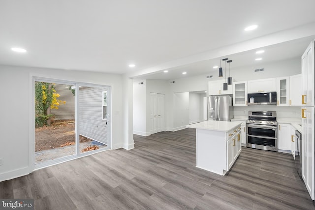 kitchen featuring appliances with stainless steel finishes, white cabinetry, hanging light fixtures, and a kitchen island