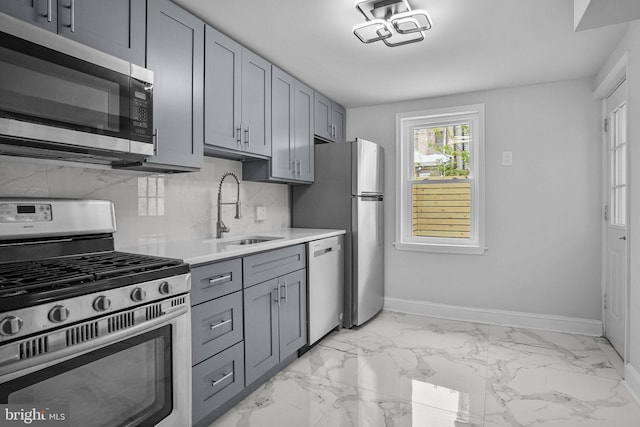 kitchen with tasteful backsplash, gray cabinets, sink, and appliances with stainless steel finishes