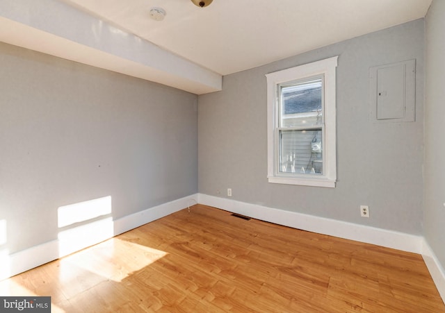 unfurnished room featuring electric panel and light hardwood / wood-style flooring