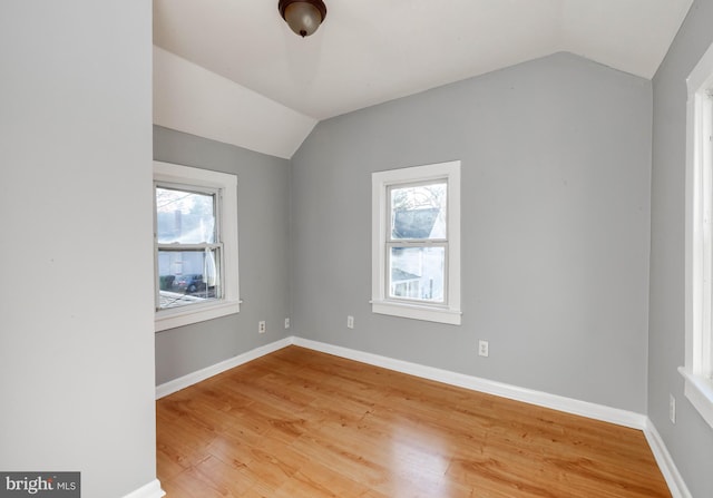 unfurnished room with a wealth of natural light, lofted ceiling, and hardwood / wood-style flooring