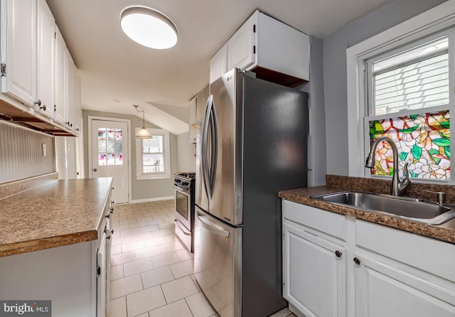 kitchen featuring appliances with stainless steel finishes, sink, light tile patterned floors, decorative light fixtures, and white cabinetry