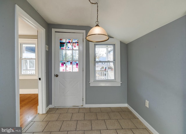 doorway with light tile patterned floors and vaulted ceiling