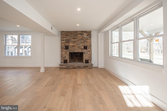 unfurnished living room featuring a stone fireplace and light wood-type flooring