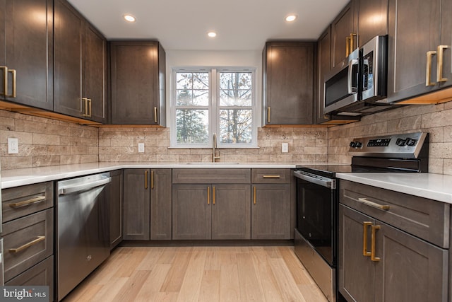 kitchen featuring backsplash, light hardwood / wood-style floors, sink, and appliances with stainless steel finishes