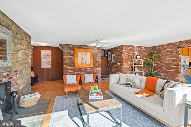 living room with hardwood / wood-style flooring, a large fireplace, and ceiling fan