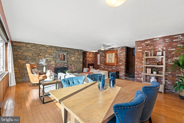 dining room with light hardwood / wood-style floors, a large fireplace, and ceiling fan