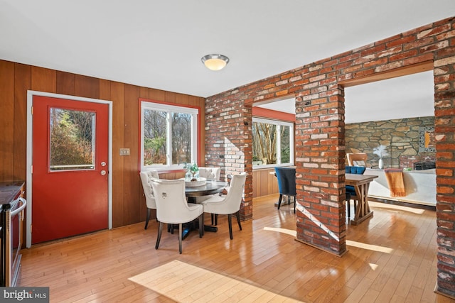 dining area with light wood-type flooring and wood walls