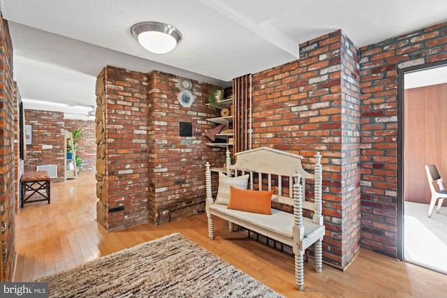 living area featuring hardwood / wood-style flooring and brick wall