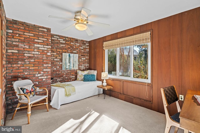 carpeted bedroom with ceiling fan, brick wall, and wooden walls