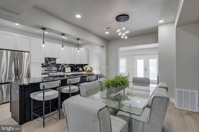 dining space featuring sink, light hardwood / wood-style floors, and french doors