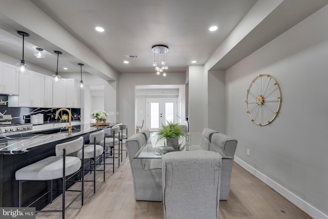 dining room featuring french doors, sink, and light hardwood / wood-style flooring