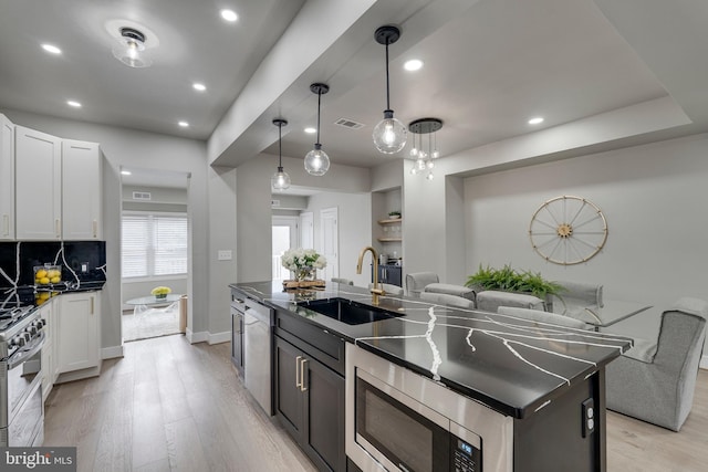 kitchen featuring sink, pendant lighting, light hardwood / wood-style floors, a kitchen island with sink, and white cabinets