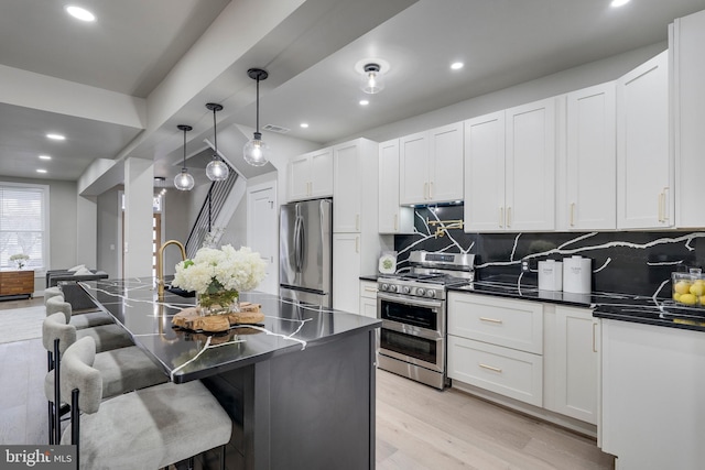 kitchen featuring light hardwood / wood-style flooring, tasteful backsplash, a kitchen bar, white cabinetry, and stainless steel appliances