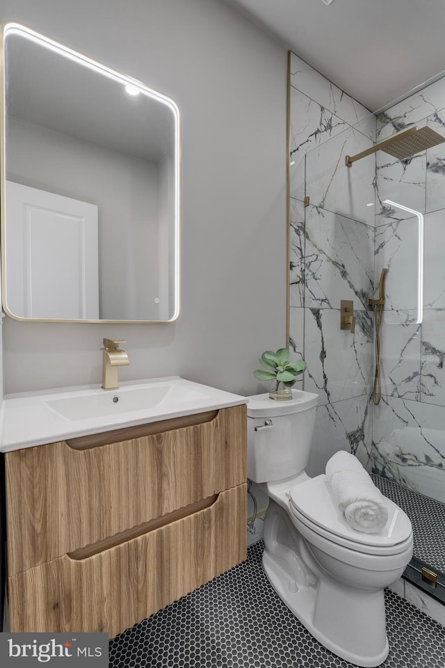 bathroom featuring a tile shower, tile patterned floors, vanity, and toilet